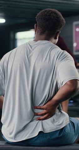 Man, fitness and back pain with discomfort in gym for workout accident, sprain or strain. Active, male person or sore spine with ache, injury or bad posture for overworked exercise or muscle tension