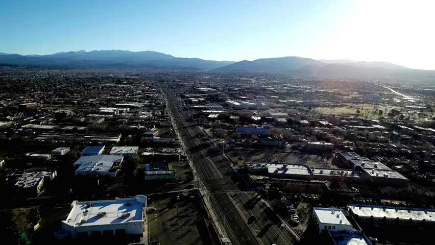 Aerial view of Phoenix city skyline with surrounding mountains under clear sunny skies, ideal for travel, urban, and landscape projects.