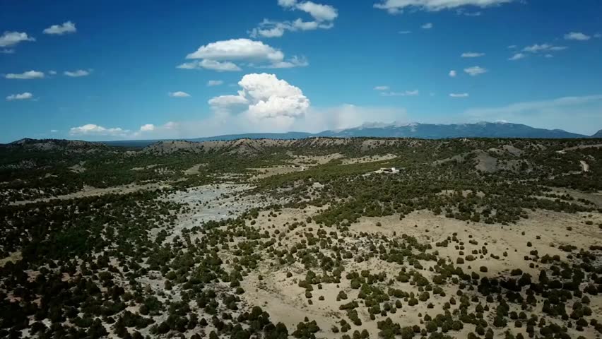Desert mesa with mountains under a clear blue sky in New Mexico, perfect for nature, travel, and scenic landscape projects.