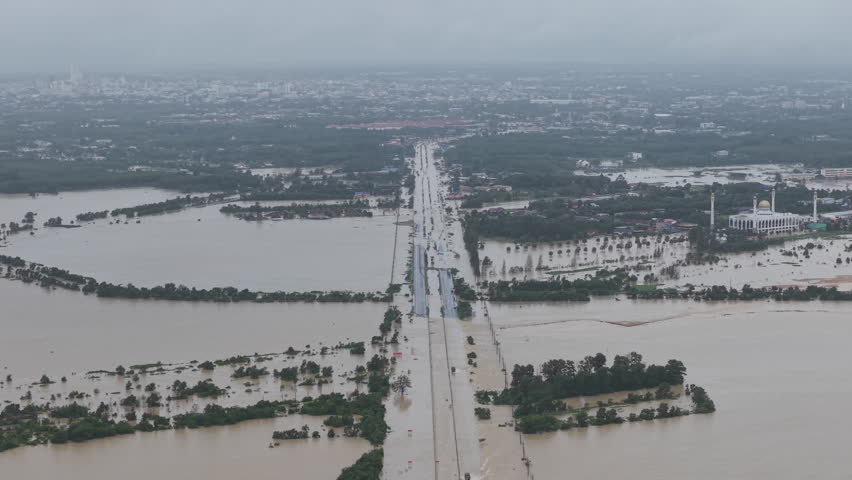 Drone shot of a flooded highway in Hatyai, Thailand, showing deep brown water covering the road and surrounding landscape in November 2025.