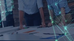 Two male colleagues leaning over desk in office showing animated teal network linking finance icons. Business, collaboration, digital, modern, innovation, finance, teamwork - Powered by Shutterstock - Get 15% off with code: PIKWIZARD15