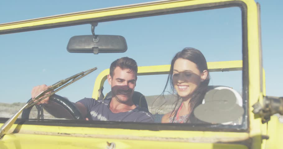 Driver grabbing phone copilot leaning sharing joy while moving travel icons floating on windshield. Couple, open-top, jeep, roadtrip, device, yellow, outdoors