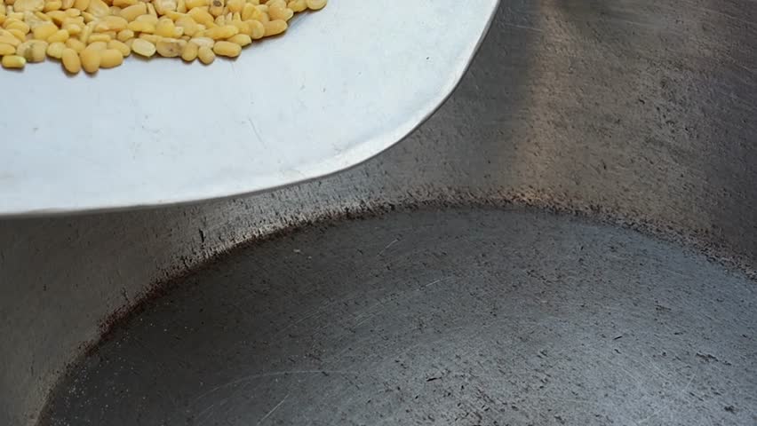 Yellow split mung beans pouring from metal scoop