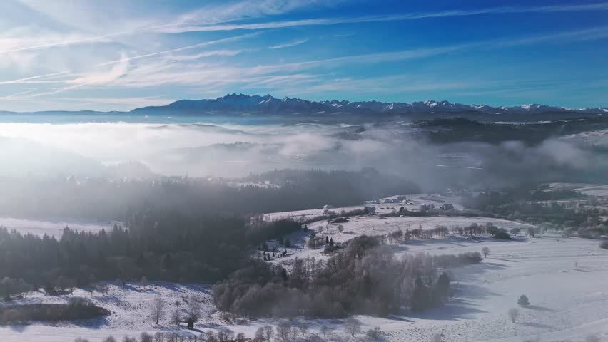 A majestic aerial view of the rural snowy winter landscape at sunny day, featuring the High Tatras National Park mountains in Poland