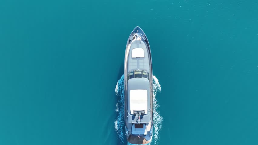 Ocean Cruiser: A sleek yacht gracefully carves its way across the tranquil ocean waters, leaving a trail of white foam in its wake. Mountains frame the distant horizon. 