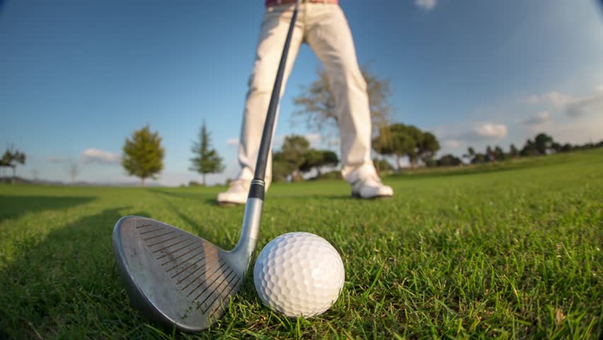 Golfer taking a shot on a sunny golf course, focusing on technique and precision, enjoying outdoor sports and recreational activity.
