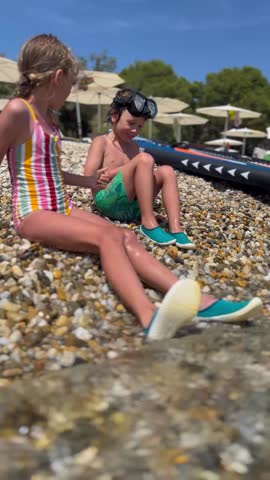Two children playing at the seaside with stones