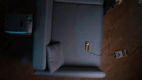 Cozy living room with a grey sofa, retro game console and two wired controllers hooked to a projector, casting classic video game nostalgia on the screen - Powered by Shutterstock - Get 15% off with code: PIKWIZARD15