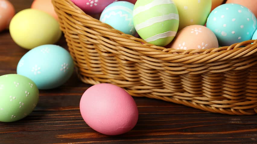 Woman painting Easter egg at wooden table, closeup
