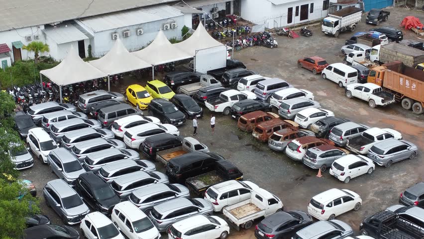 Aerial view of cars parked in a row for auction, there are various types of cars, customers can be seen looking at the cars