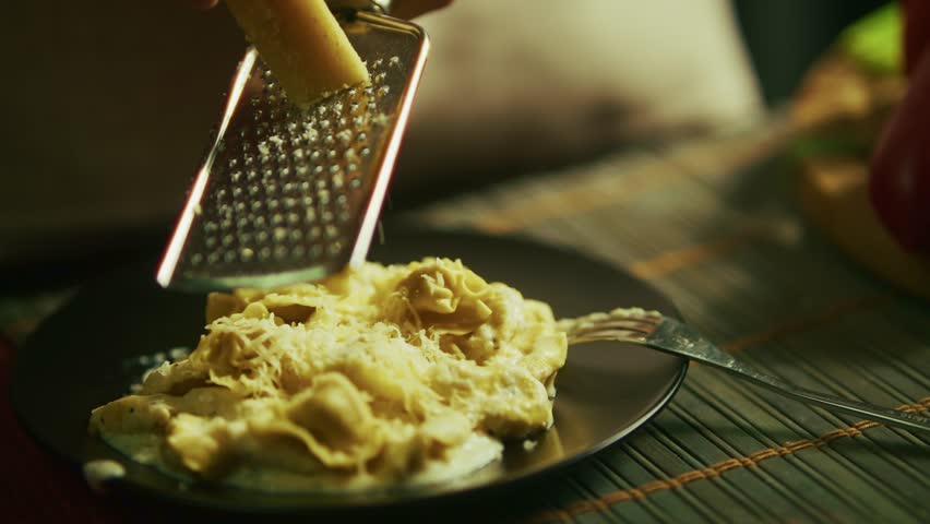 Pouring  Olive Oil Onto Hot Ravioli Pasta With Grated Hard Cheese. Authentic Italian Dinner Preparation. Mediterranean Gastronomy. Traditional Tortellini In Creamy Sauce. Home Cooking Tasty Dish Pasta