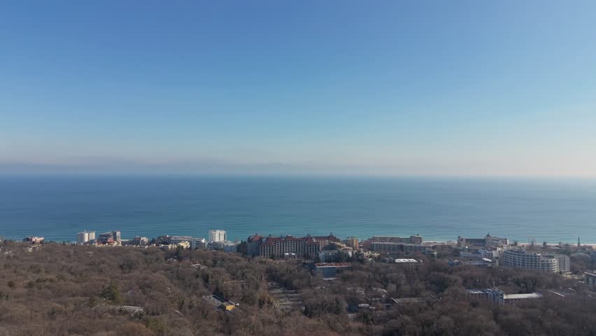 Aerial view of forested hills under clear blue sky, calm countryside scenery, natural landscape, peaceful environment, cinematic drone footage.