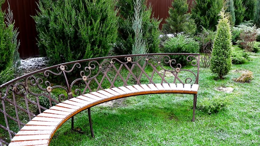 Junipers and a semicircular bench with forged elements in the garden