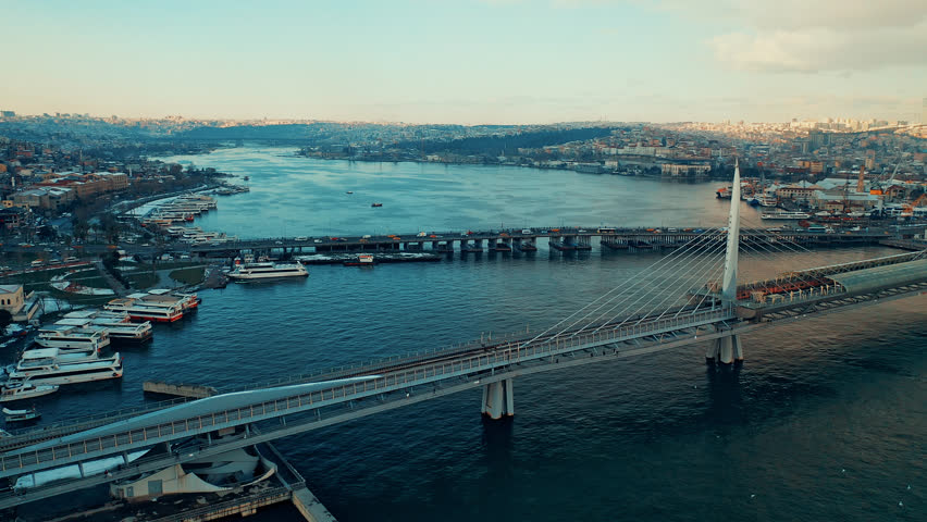 Halic Metro Bridge aerial view of the modern transit bridge over Golden Horn. Cinematic drone flight showing the metro station and Istanbul skyline.