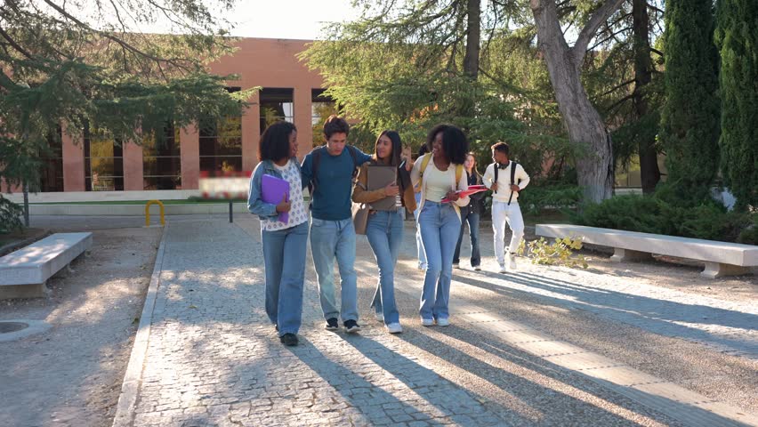 Group of happy young multiracial students walking together on the university campus. Diverse college friends laughing and enjoying their time
