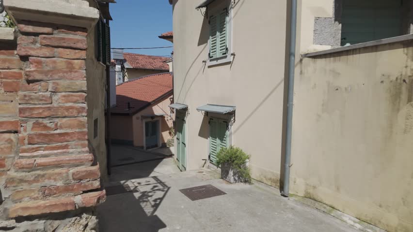 Walking along the street between romantic old Mediterranean houses in Volosko, Croatia. Slow motion building exterior with green window shutters. Sunny day in the old town of a coastal city.