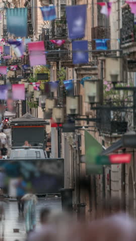 Tourists and locals walking and shopping in Rue Sainte-Catherine timelapse, Bordeaux, France. The longest pedestrian street in the country. Atmosphere of urban life. Colorful flags decorate the street