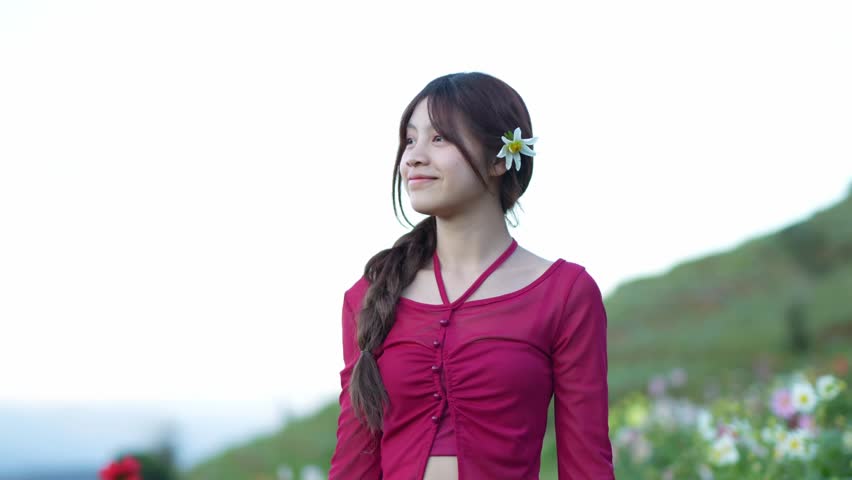  A young woman stands amidst a field of flowers at sunset.