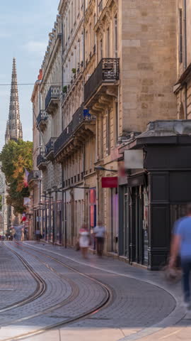 Timelapse of Bordeaux Cathedral (Cathedrale Saint Andre) from Vital Carles street, featuring a moving tram in the historic city. People wait at the tram stop. A symbol of Bordeaux