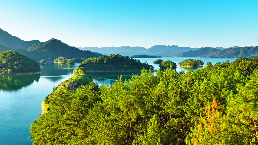 Aerial shot of beautiful blue lake with green islands and mountain natural landscape in the morning. Famous Qiandao Lake scenery in Hangzhou, China. 