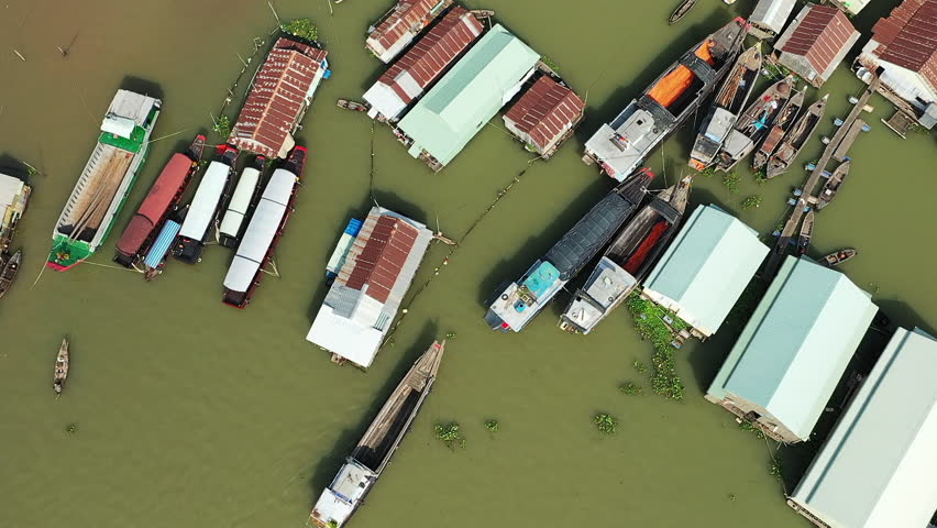 Aerial view of floating houses and boats on the river in Chau Doc, Vietnam, showcasing a unique riverside community. Traditional wooden boats and stilted structures are visible on the murky water.