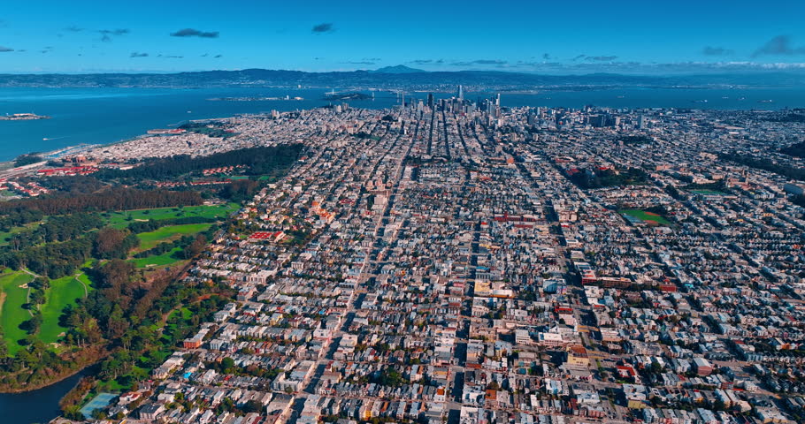 Dense urban landscape of modern residential area in San Francisco, CA, USA. High-rise downtown against blue waterscape at backdrop. Aerial view.