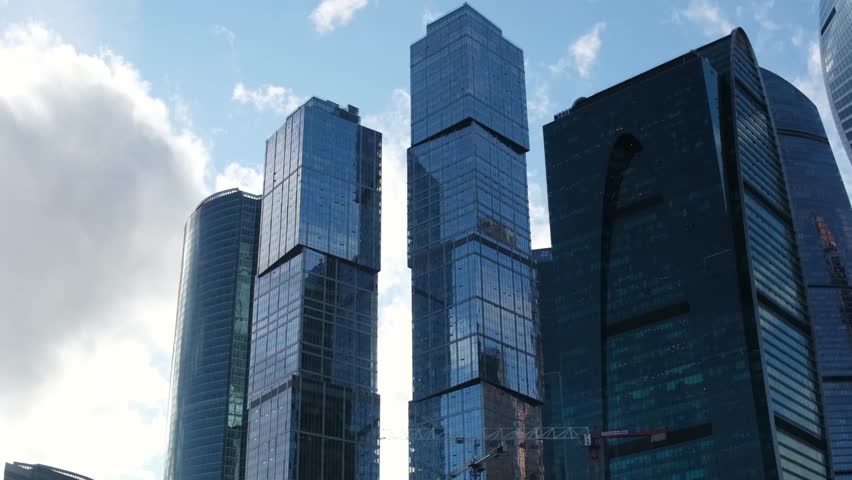 September 11, 2025, Moscow, Russia. Tall buildings rise against a bright blue sky filled with clouds. The modern architecture shines in the sunlight, showcasing the cityscape.