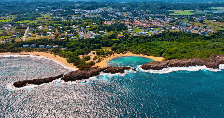 Iconic beaches with clear turquoise water. Aerial view on the stunning Mar Chiquita Beach in Manati, Puerto Rico. Cityscape with lush greenery at backdrop.