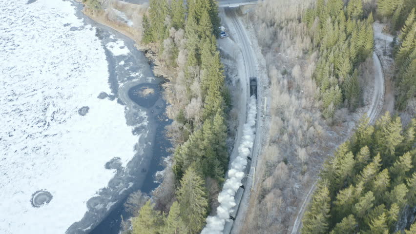 Aerial Drone View of Historic Steam Train Passing Under Bridge in Winter Forest