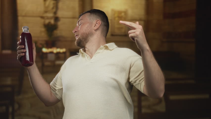 Man holding bottle and pointing finger in church building while showing bare forearm and raised hand; skepticism.