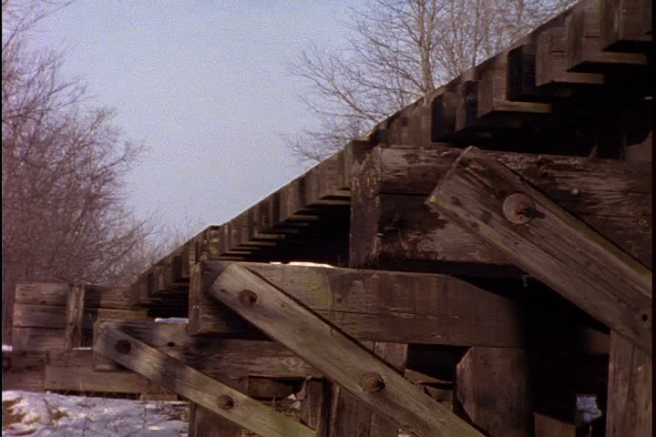 Historical reenactment on Mid Continent Railway, New Freedom, Wisconsin. CU low angle wooden trestle bridge. 1885 steam train approaching camera. It passes over bridge. 
