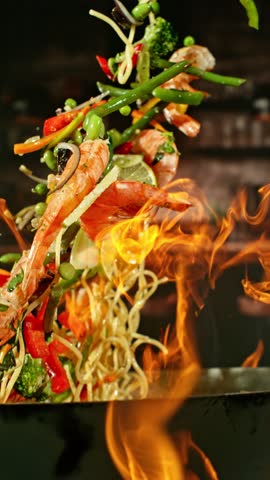Super Slow Motion of Flying Asian Meal with Meat and Vegetable. Filmed on High Speed Cinema Camera, 1000 fps. Blur Kitchen Interior on Background.