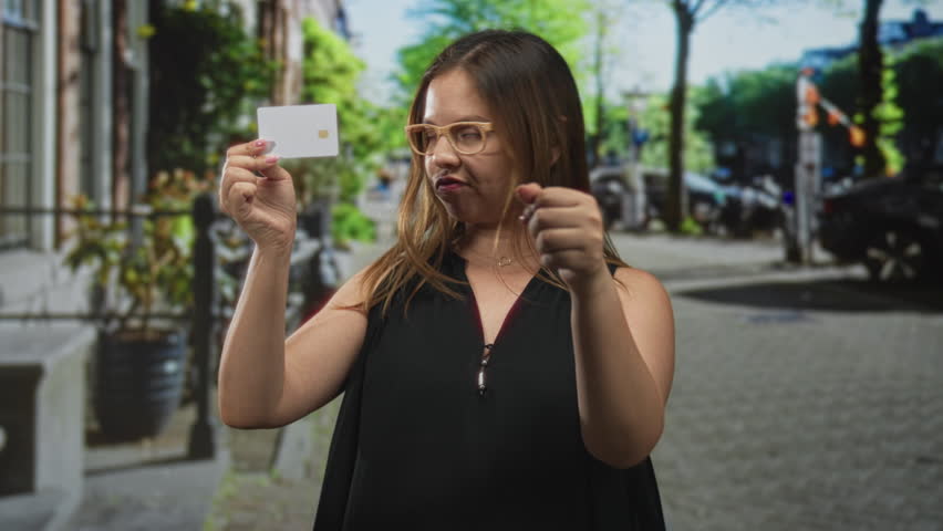 Woman holding white card with palm raised on a street, hand showing card up; defiance refusal consumer awareness.