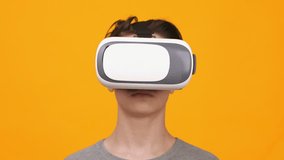 Young Person Using Virtual Reality Headset in Front of Bright Orange Background While Exploring Digital Environments - Powered by Shutterstock - Get 15% off with code: PIKWIZARD15