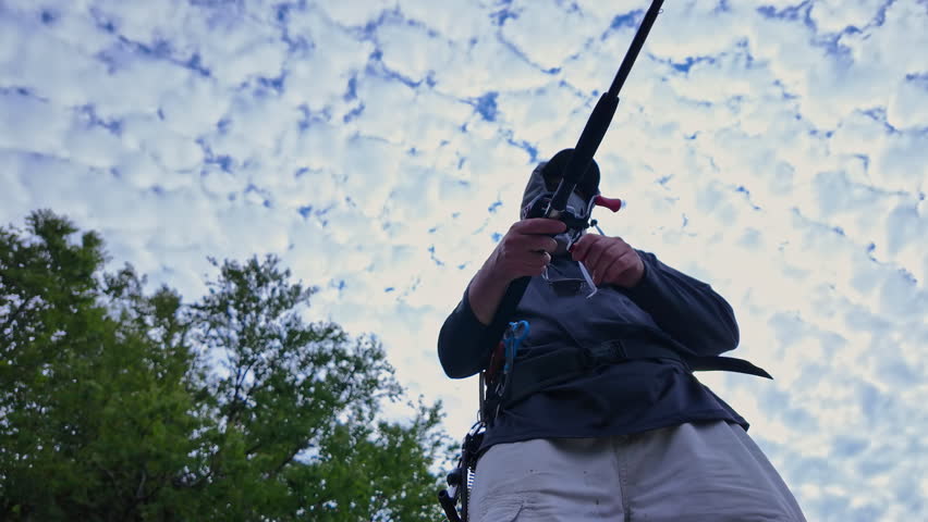 View up from below of an angler cast and reel casting rod and using walk the dog technique fishing action with top water lure to catch top water fish such as smallmouth or largemouth bass.