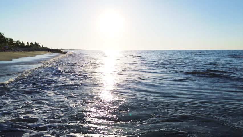 Traveling out shot of blue ocean waves and bright sun reflection, Backward motion over the ocean during a sunny day with blue water. High quality 4k footage