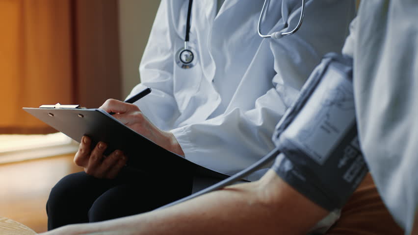 Doctor Checking Blood Pressure and Taking Notes in a Medical Appointment Setting