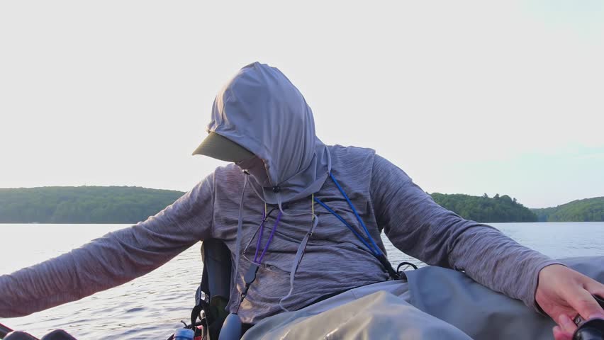 Kayak fishing, man display fresh catch small pike fish at lake Simcoe in Ontario, Canada, at twilight nature and tranquility. Angler enjoys solitude during hot summer evening.