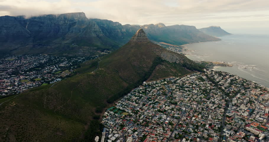 Cinematic aerial view of Cape Town cityscape in South Africa with Lions Head peak, coastal skyline and urban landscape in soft daylight. Smooth 4K drone zoom out movement for establishing shots