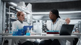 Biologist analyzes cellular samples on microscope while coworker writes research notes. Team of female scientists working together, examining sample in lab with high tech optical device gear, camera A - Powered by Shutterstock - Get 15% off with code: PIKWIZARD15