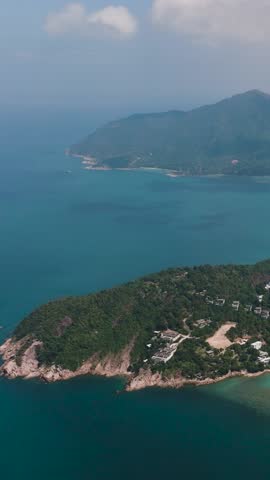 Coastline with dense forested hills and clear turquoise sea under a blue sky. Ko Pha Ngan, Thailand.