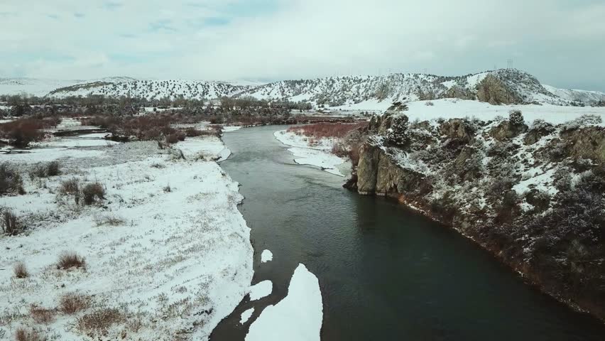 Serene snowy landscape with river flowing through rocky terrain