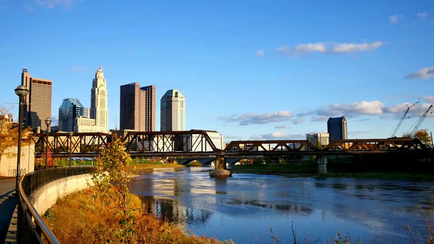 Columbus, Ohio skyline along the Scioto River on a sunny day, showcasing urban architecture, riverside scenery, and vibrant city life.
