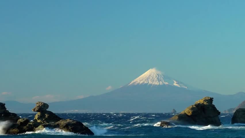 Mount Fuji rises majestically above ocean waves in Japan, showcasing stunning natural beauty, iconic landscapes, and serene coastal scenery.