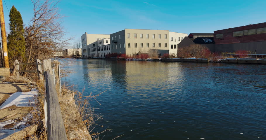 Handheld Shot of Old Historic Paper Mill Buildings alongside walking path on a clear winter day, Fox River Appleton, Wisconsin
