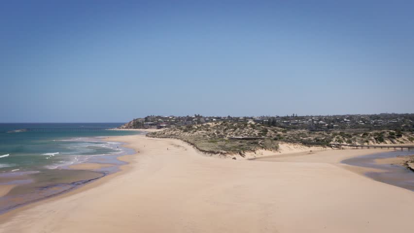Sunlit sand dunes rise behind the beach at Port Noarlunga, showcasing Australia’s coastal environment.