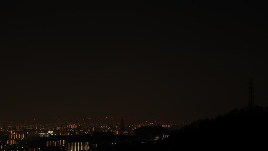 Urban cityscape at night with illuminated buildings under dark sky