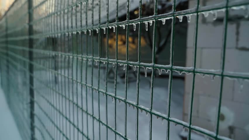 Smooth camera movement near a chain link fence covered in ice, close-up