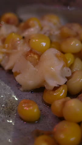 Explore Colombian street food with this vertical video showing a close-up shot of mazorca con queso being prepared. Rich colors and textures pop in this detailed culinary view.