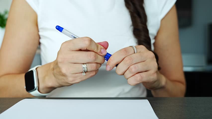 Close up of woman hand writing notes with ballpoint pen on paper in home office. Everyday paperwork task, focused documentation process and real life work routine in personal workspace.